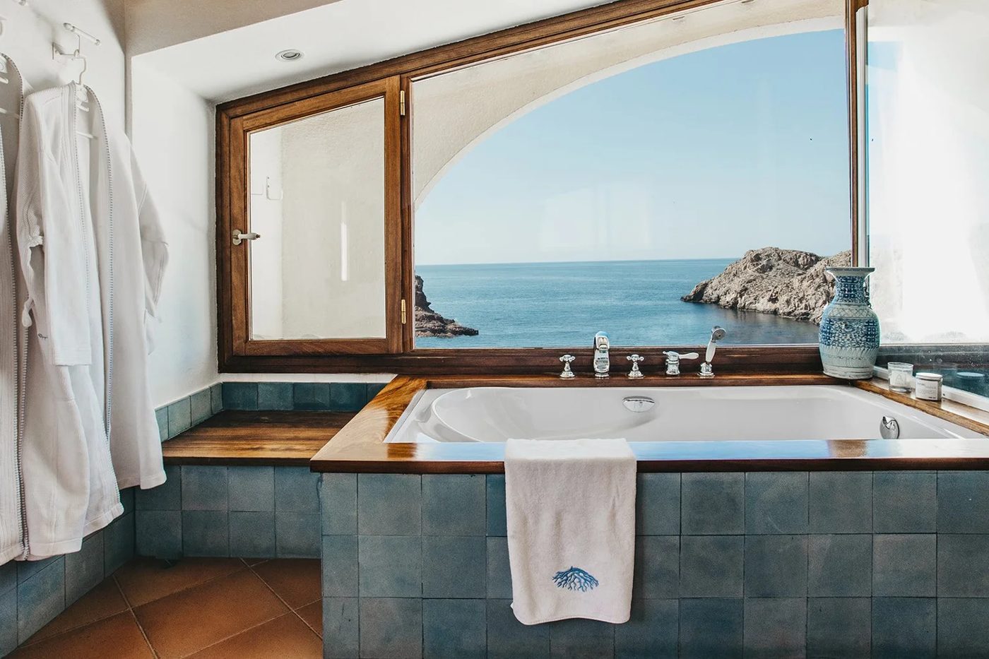 Bathtub facing an arched window over the sea