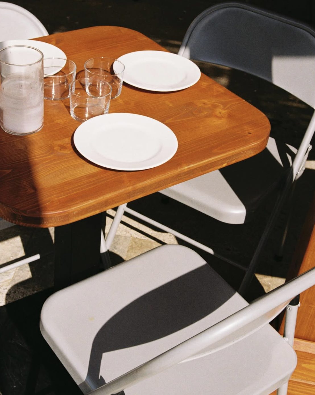 A wooden table set in the sun with folding chairs at Trozo de Oso